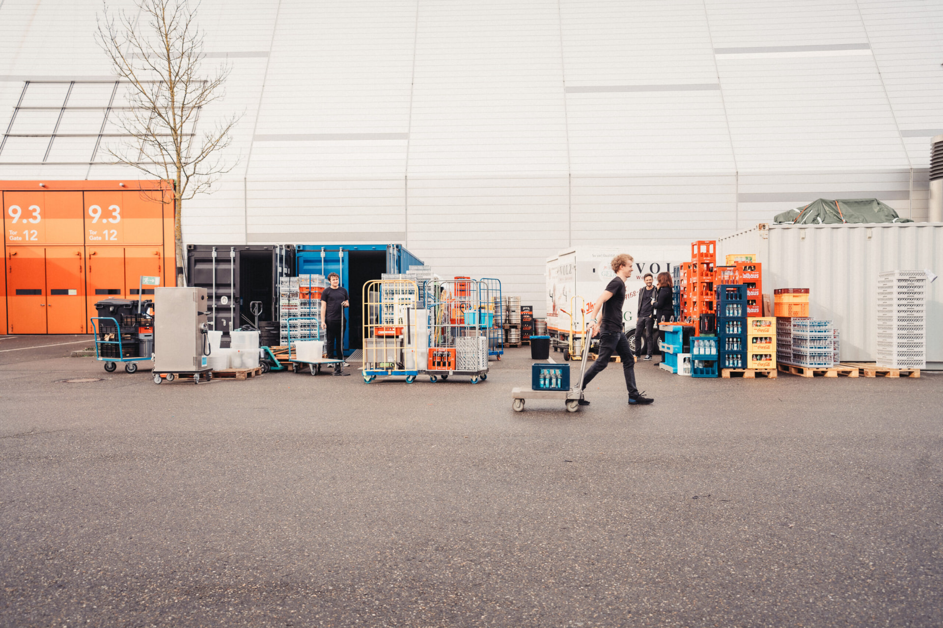 Catering-Team beim Aufbau mit Getränkekisten vor einer Messehalle